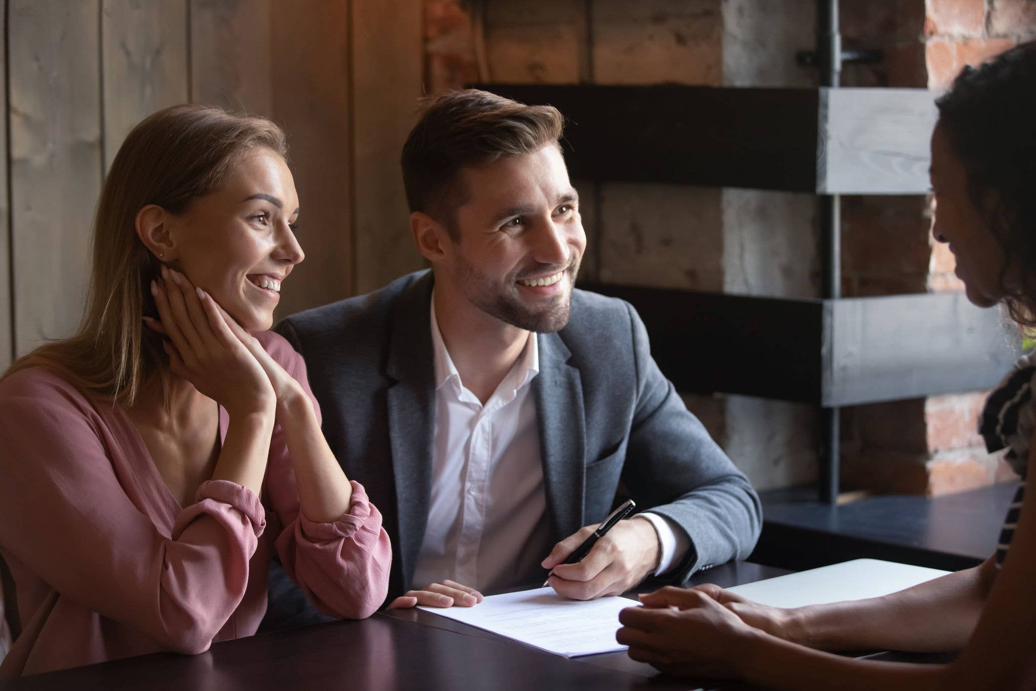Smiling man and woman at desk with insurance agent.
