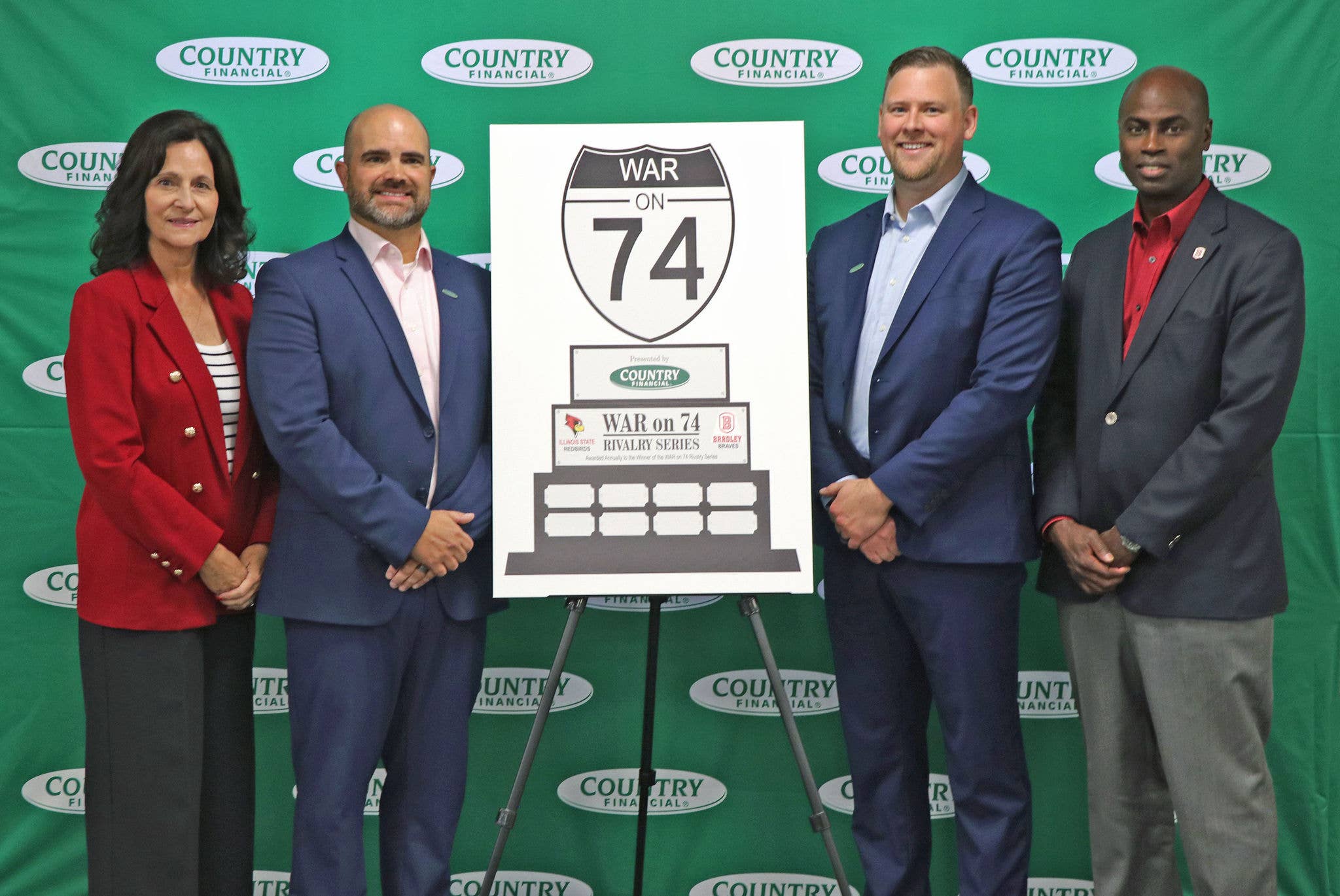 Four people standing next to a "War on 74" sign with a COUNTRY Financial backdrop