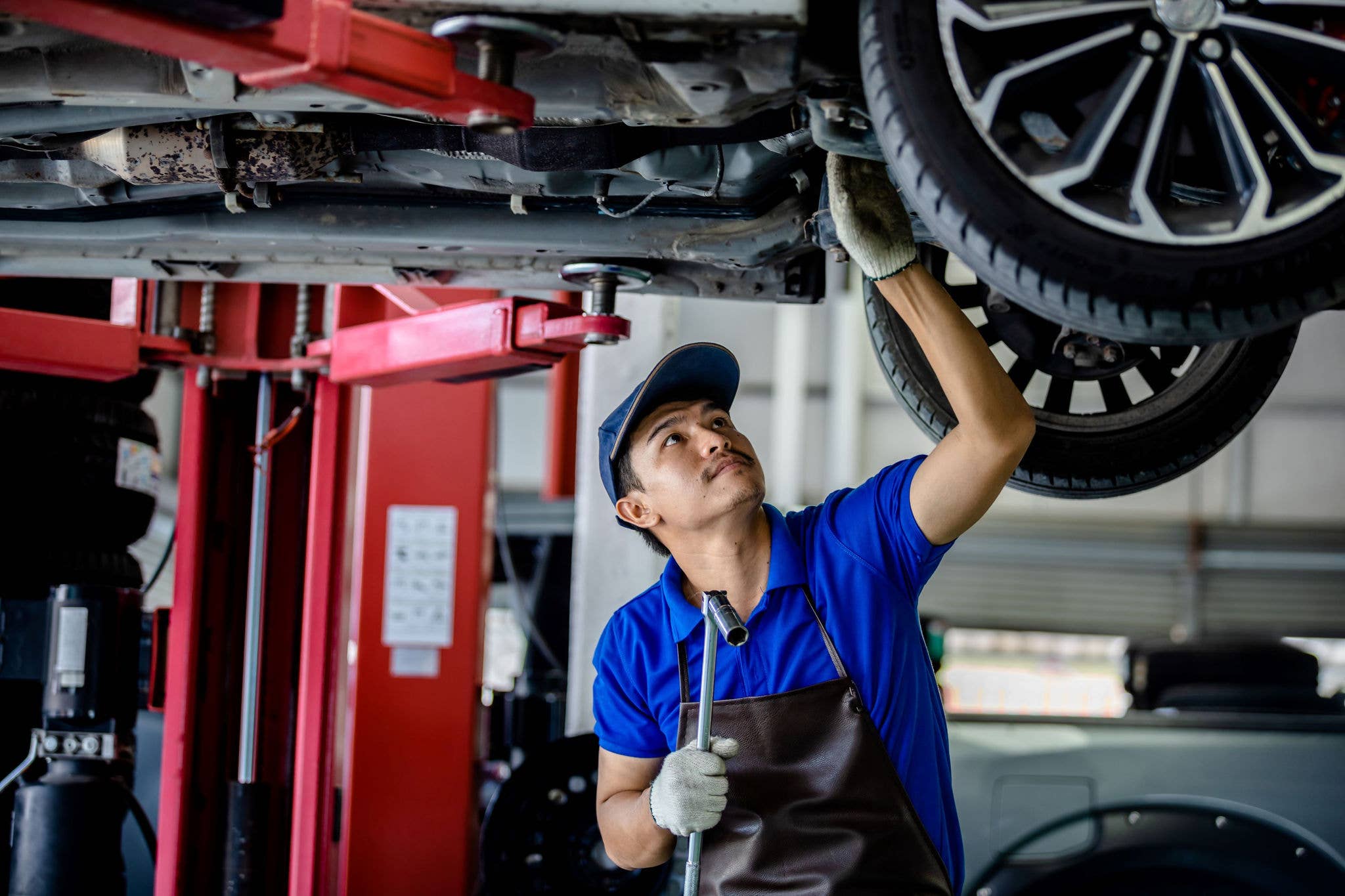 Man fixing lifted car in mechanic shop