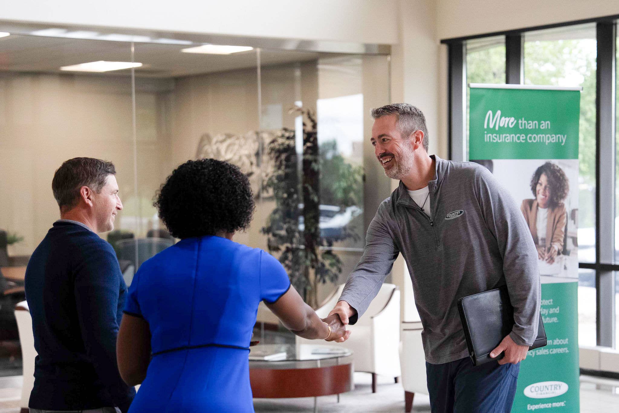 A COUNTRY Financial representative shaking hands with a client in an office, symbolizing trust and partnership.