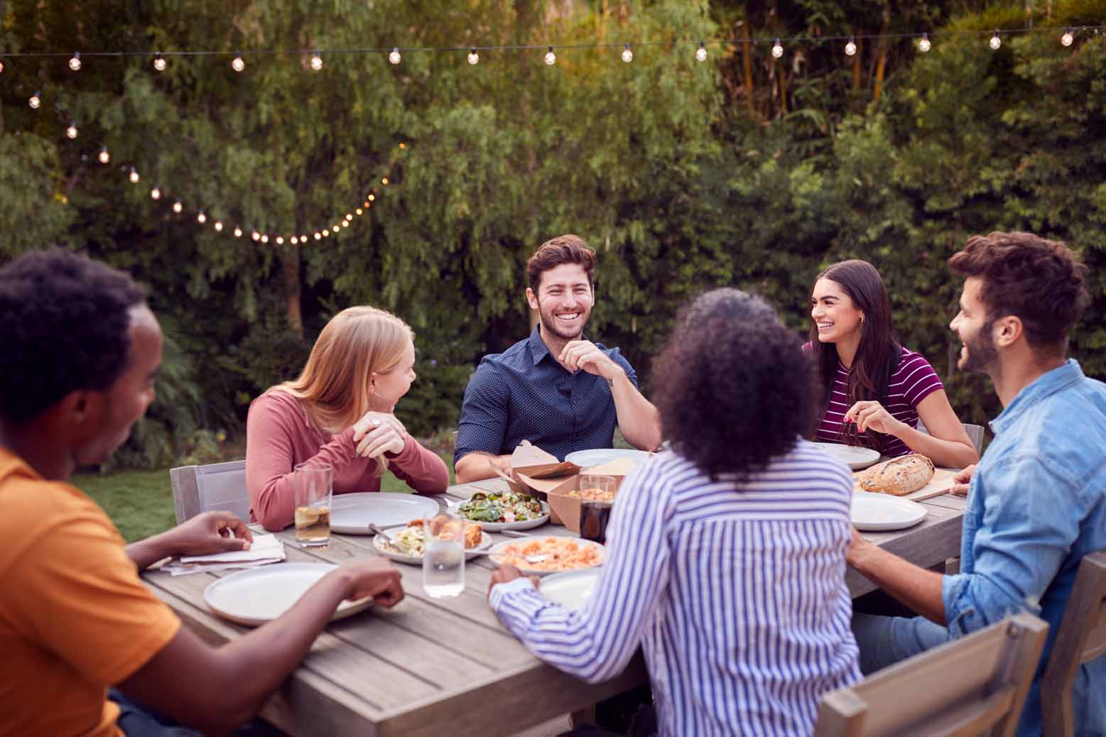 Friends sitting at table eating dinner outside