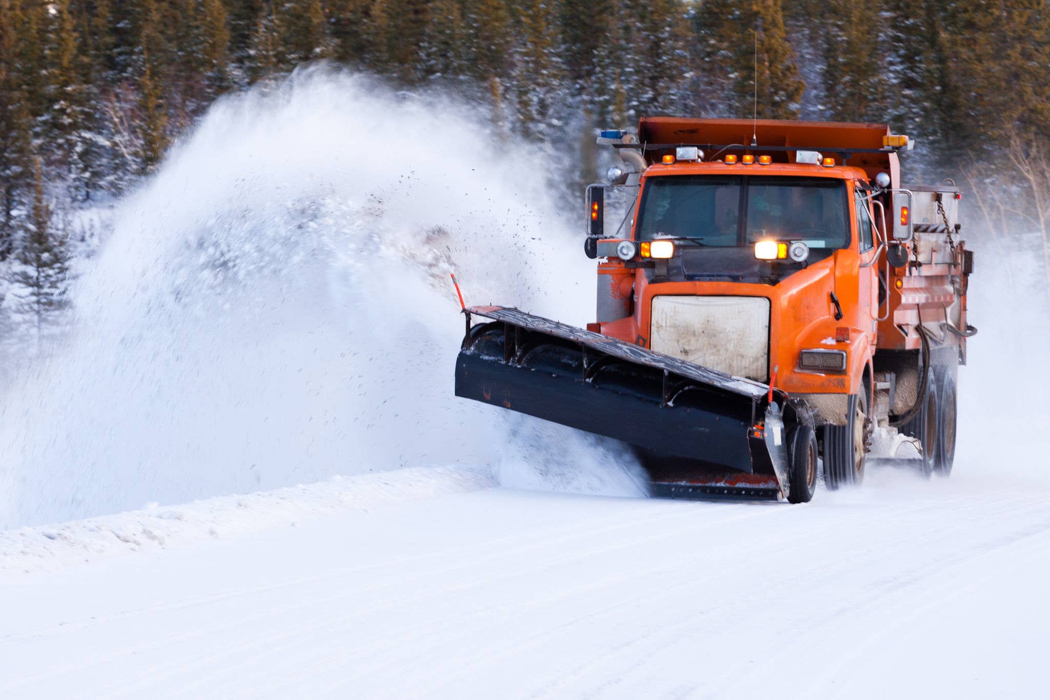 Snow plow truck clearing road after winter snowstorm blizzard