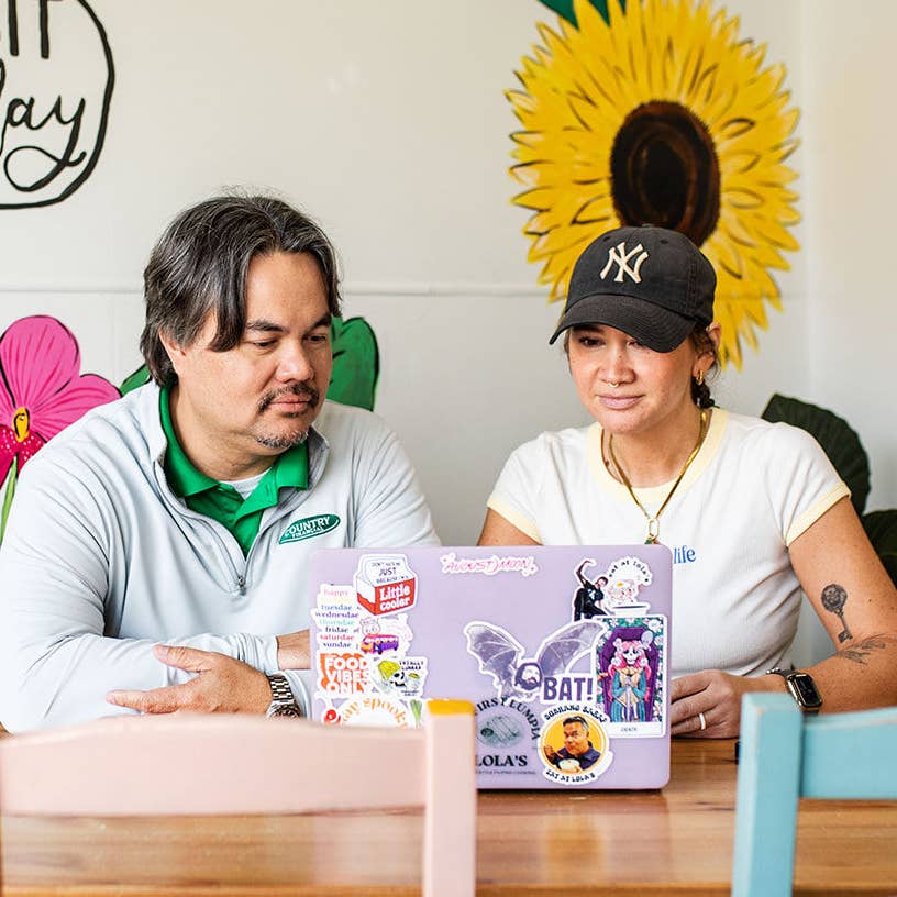 Insurance agent and client sitting at restaurant table looking on the computer