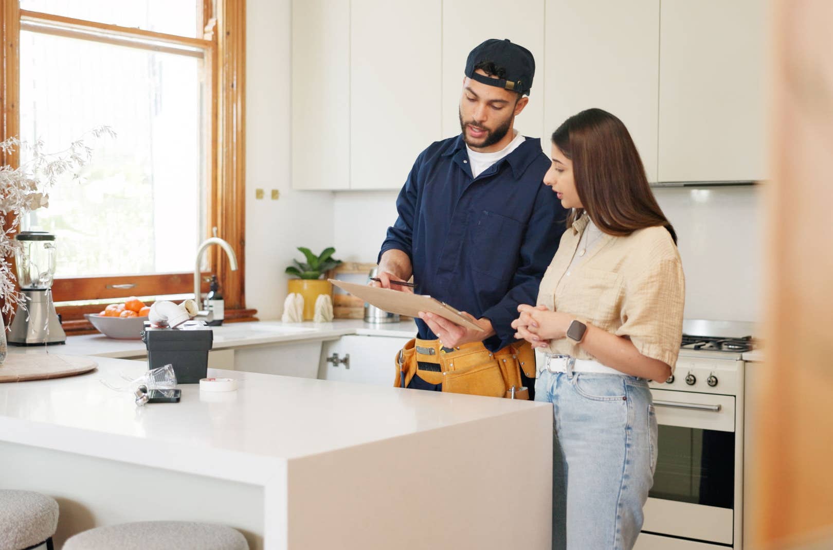 Plumber talking to client in kitchen
