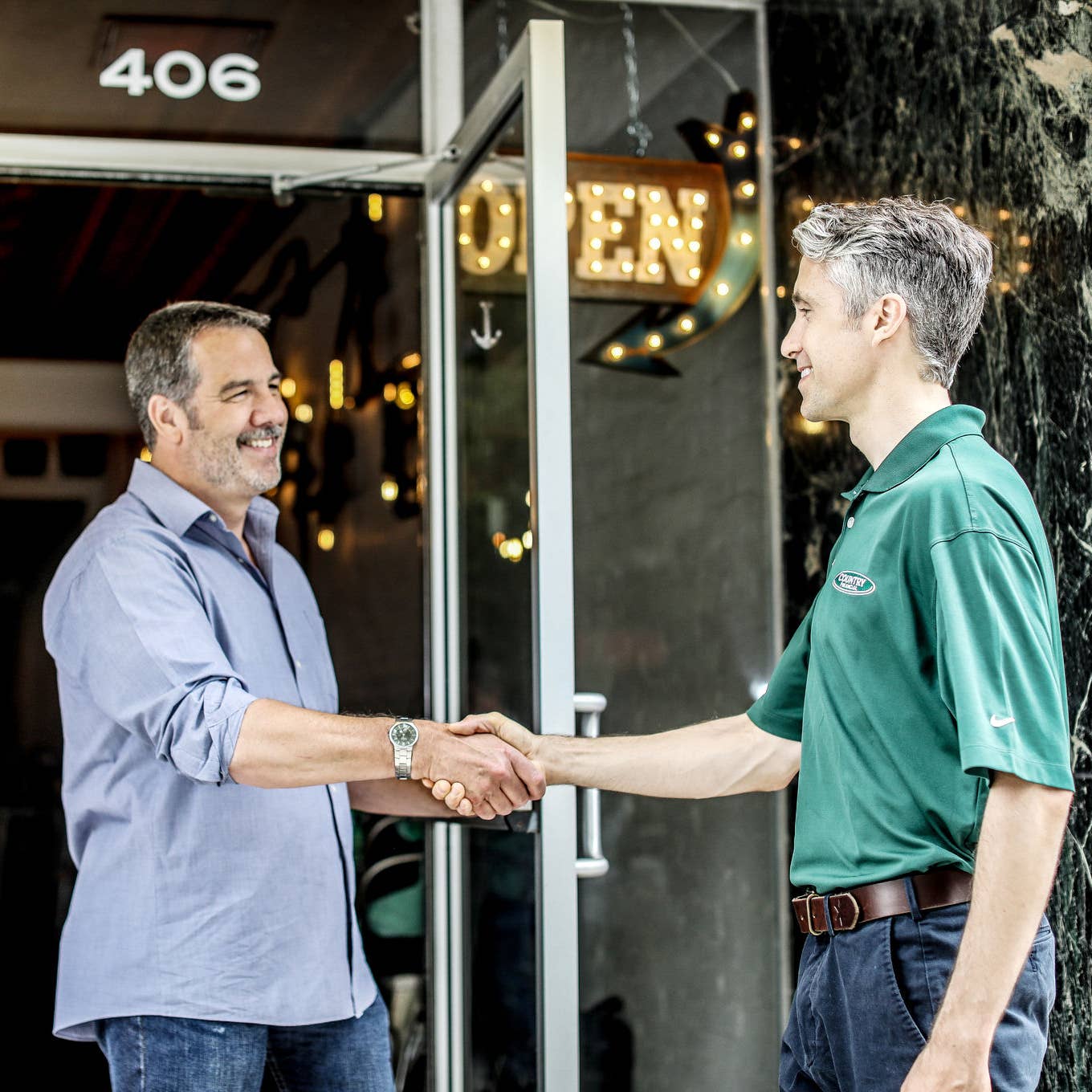 Rep shaking client's hand in the doorway of a brewery