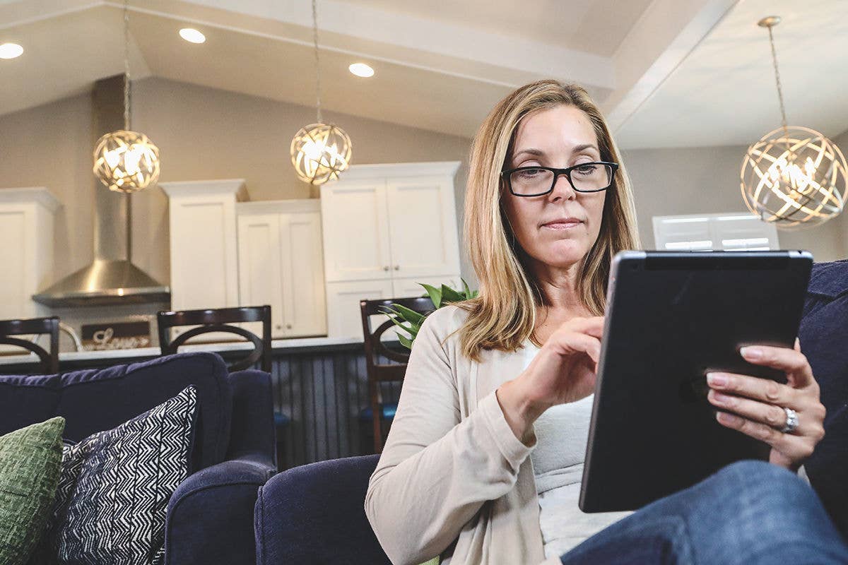 Woman in her living room reviewing an iPad.