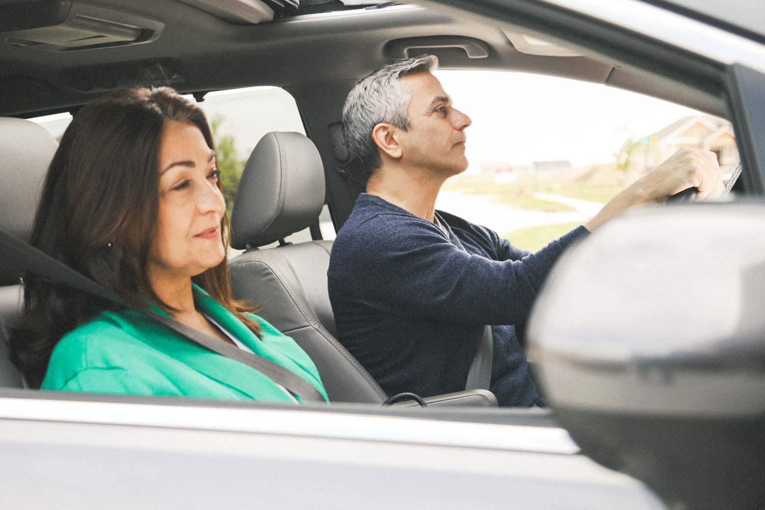 Mature couple driving a car with the windows down.
