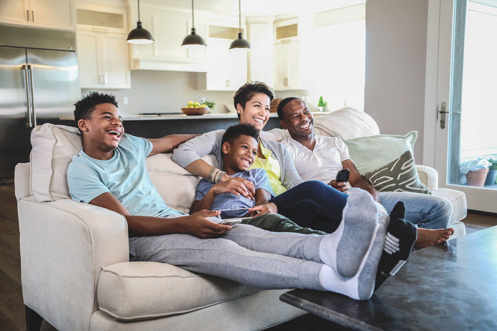 Family sites on couch in home living room.