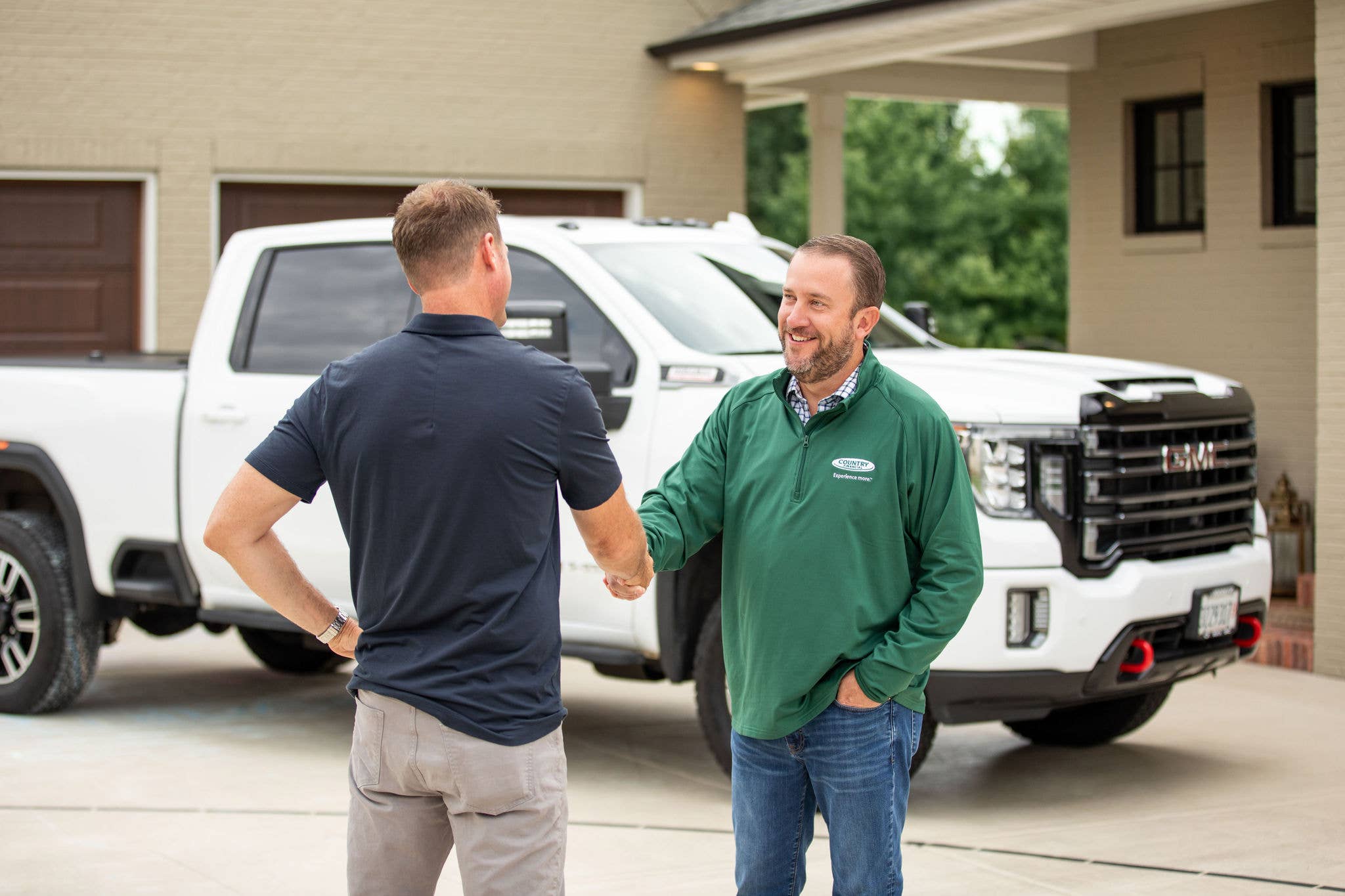 COUNTRY Financial representative shaking hands with a man near a car.