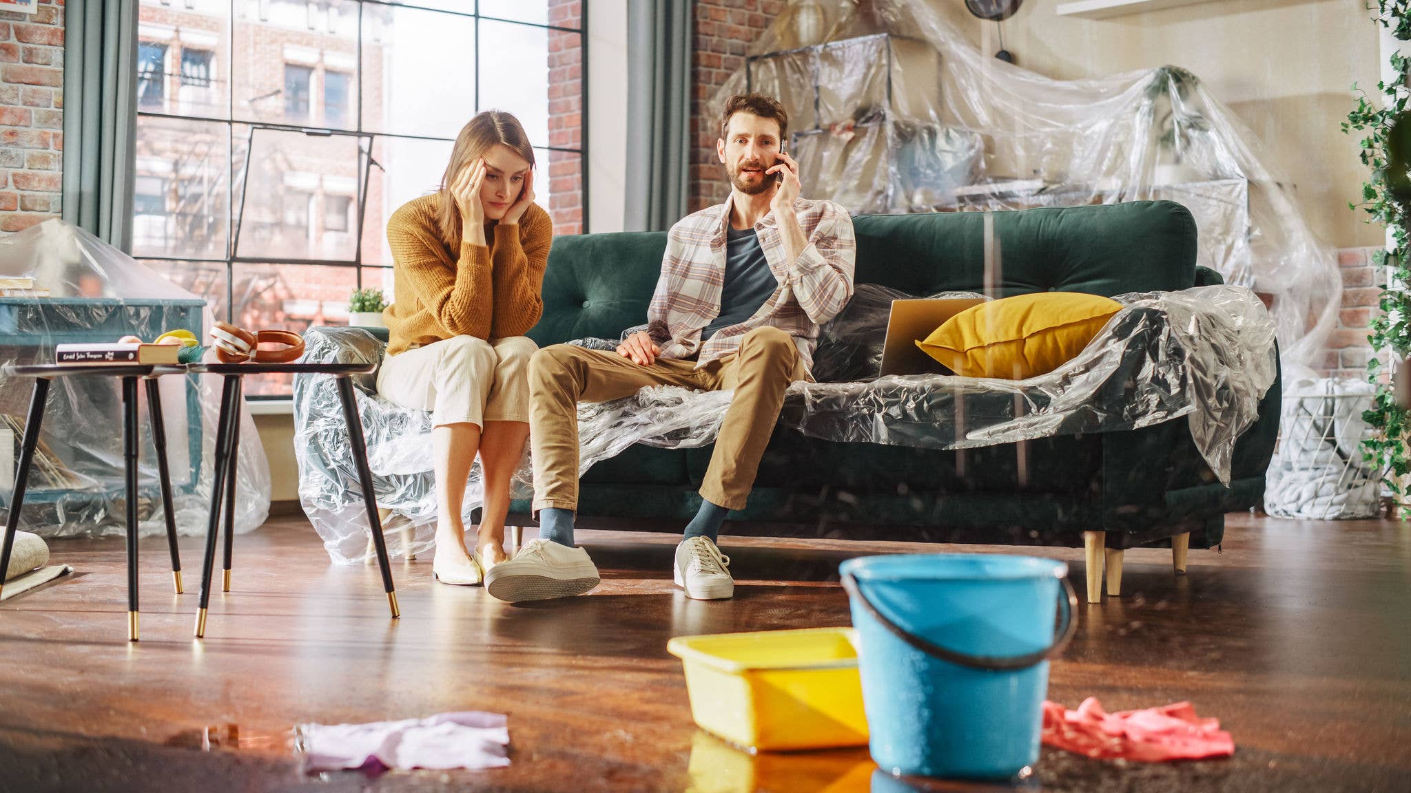 Couple sits on couch as water leaks in their home.