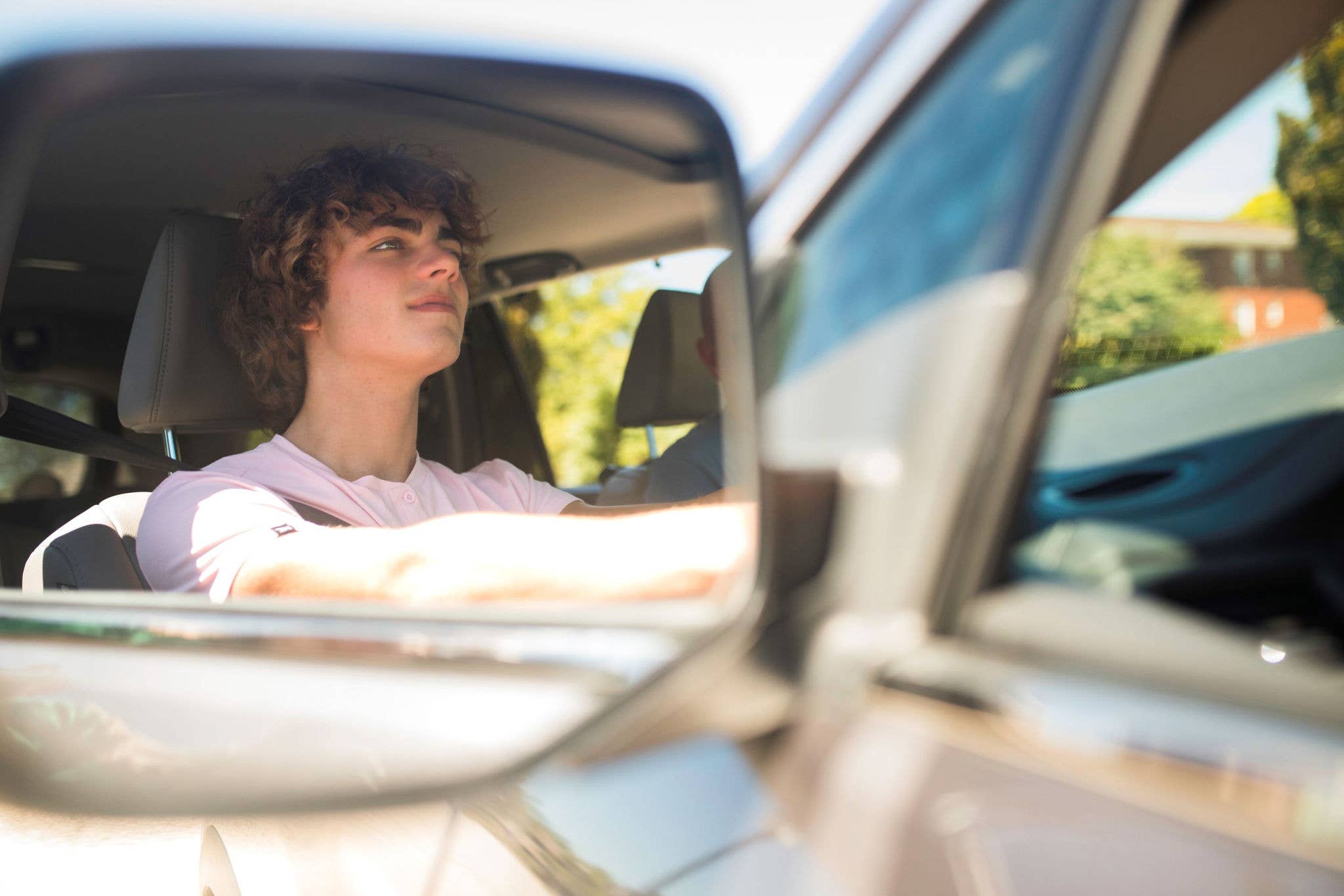 Young male driver in car mirror