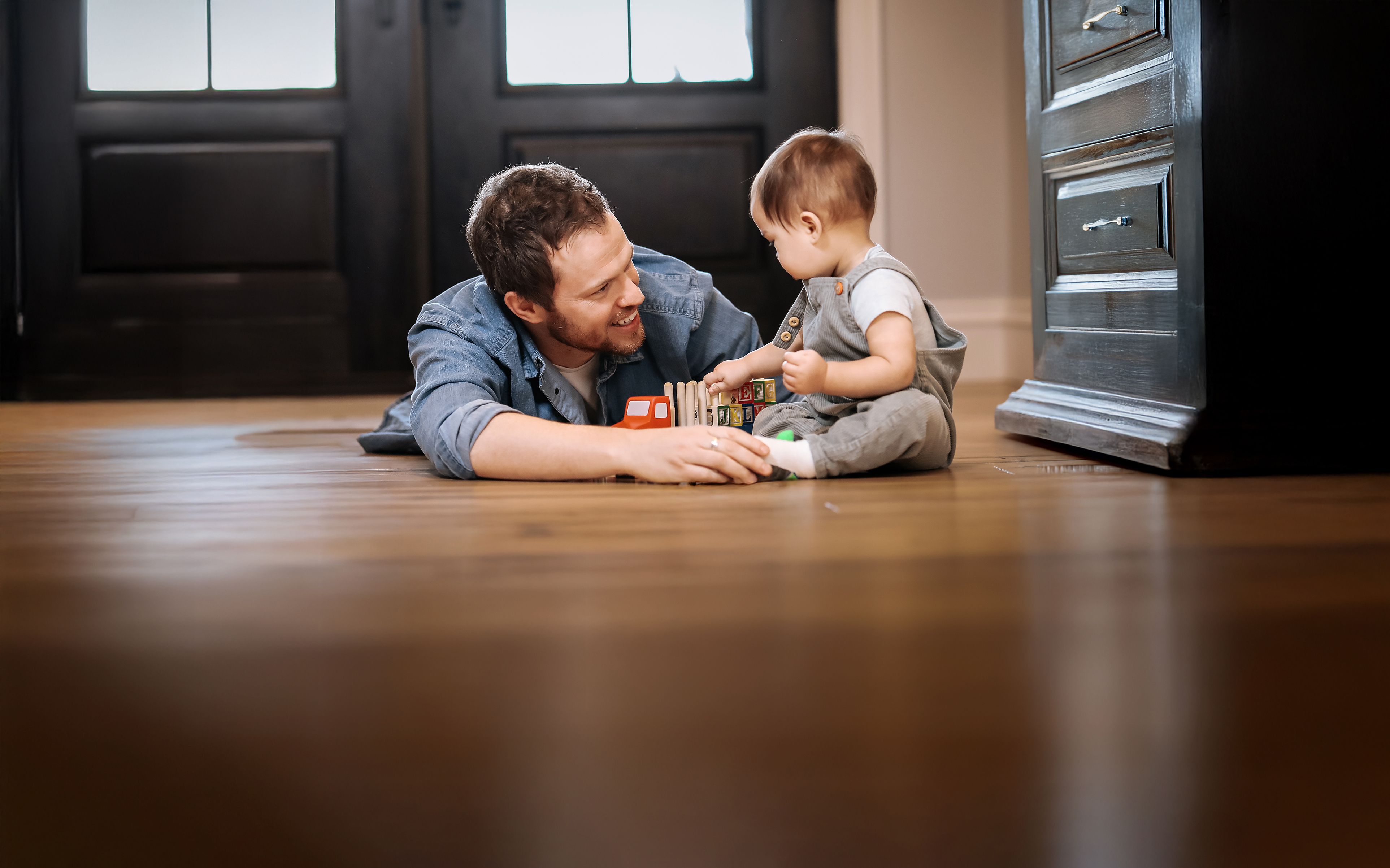 Father and child playing with blocks on floor