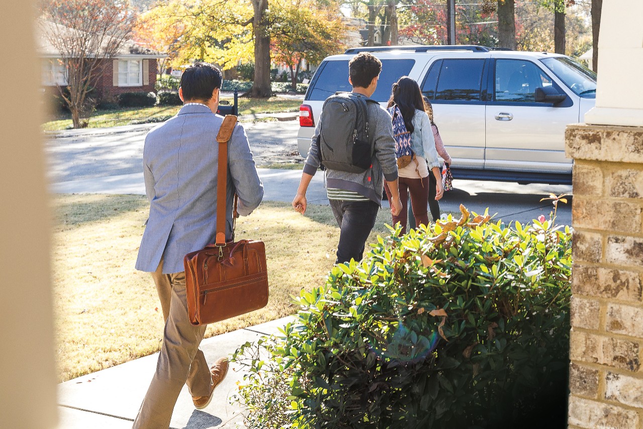 Family leaving home for work and school with SUV in driveway