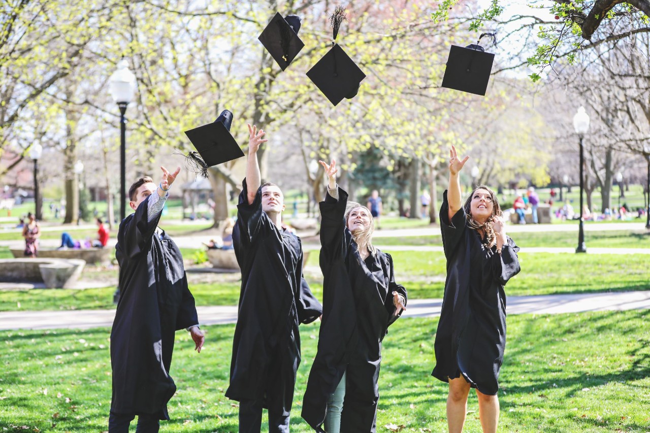 Four graduates tossing caps