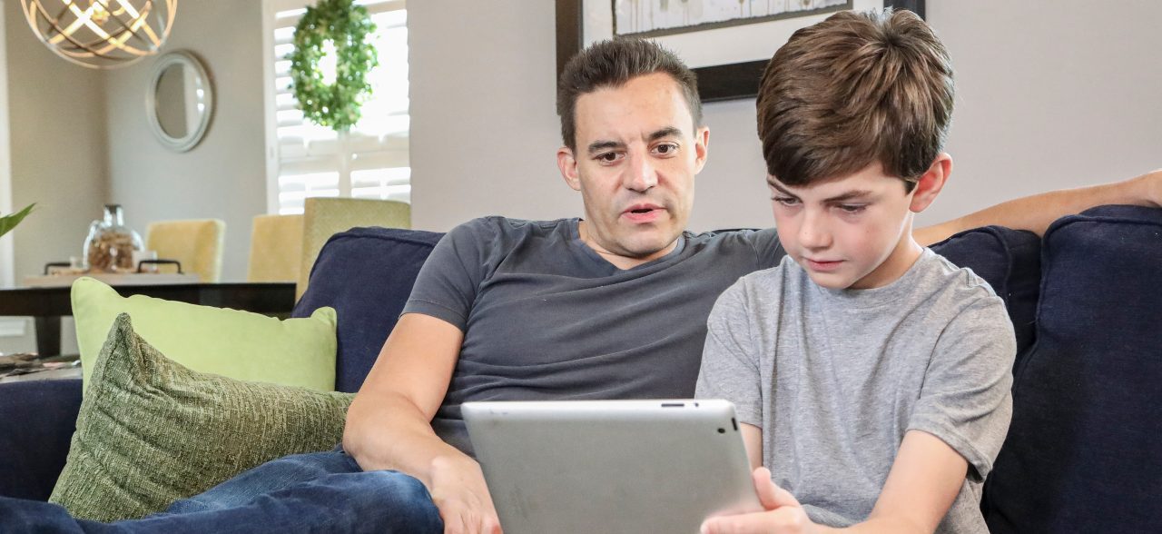 Father and son in their house with a tablet