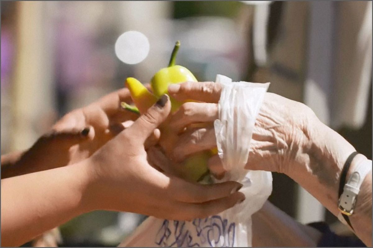 Hands exchanging yellow and green peppers at farmers market