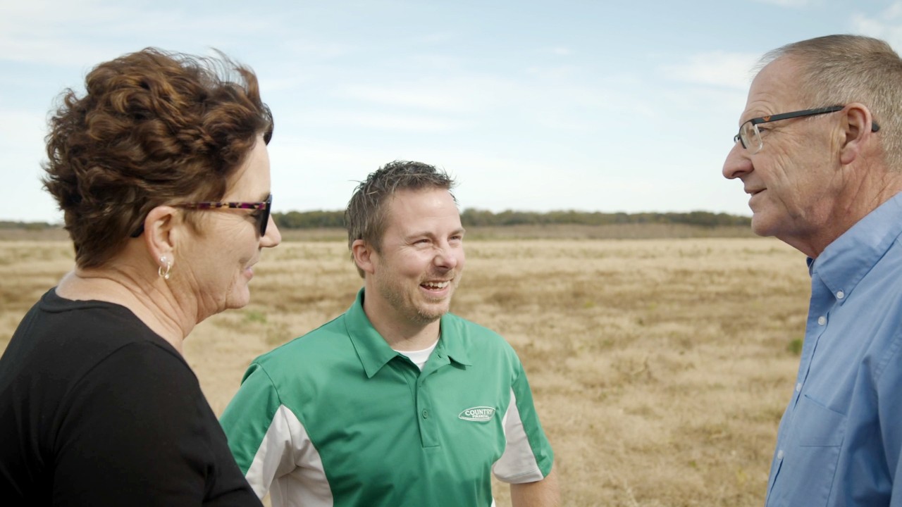 Insurance representative talking to senior couple in field