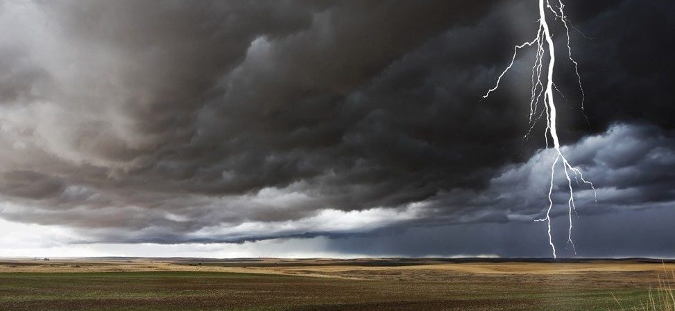 Lightning bolt striking in farm field during storm