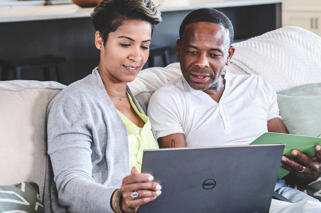 Couple looking at laptop on sofa