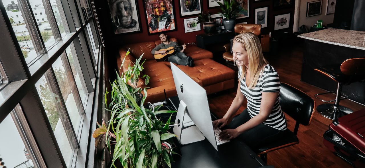 A happy young woman looking at a monitor 