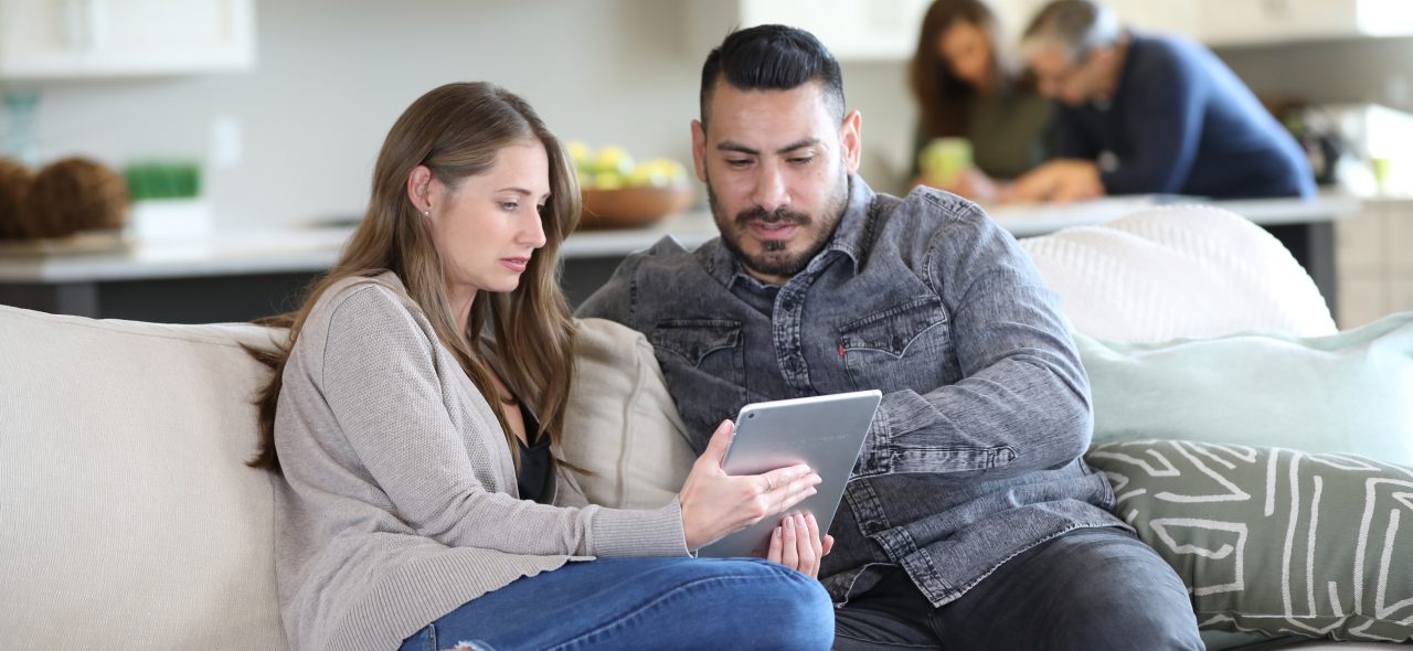 Young couple looking at tablet on sofa