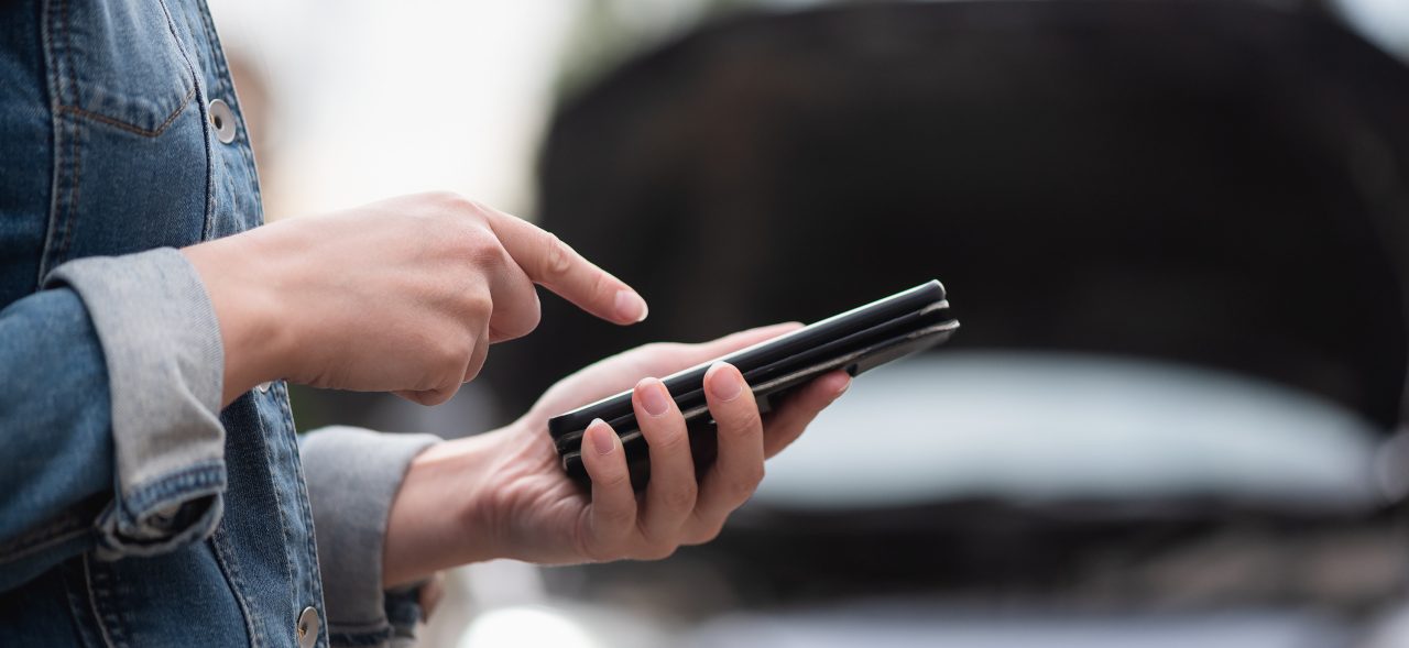 Woman with mobile phone on the broken car background. Tow truck service. Car service call.