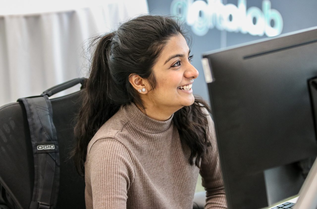 Intern smiling at computer desk in DigitaLab