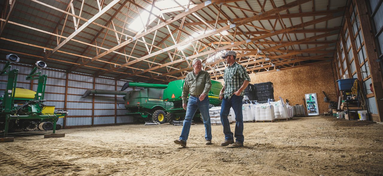 Two farmers walking inside barn