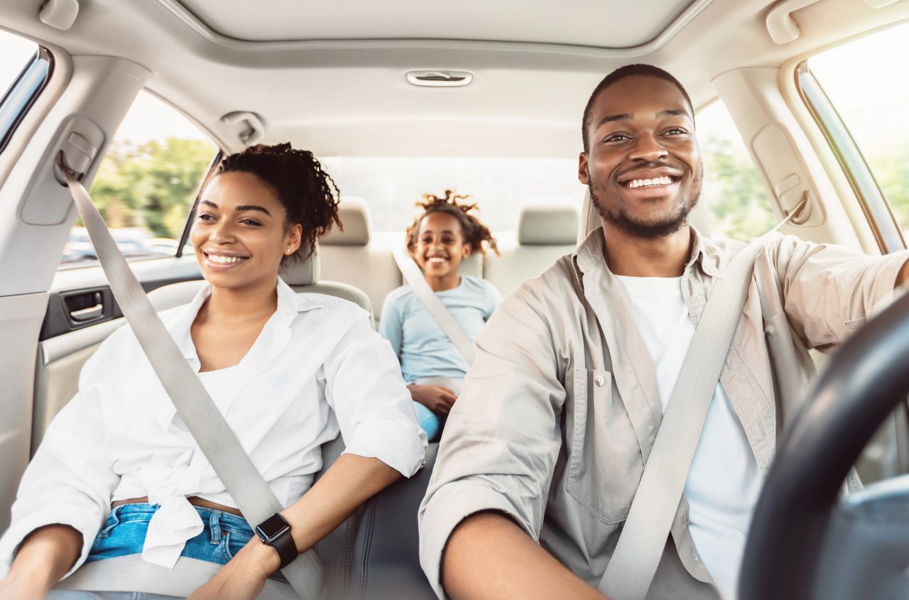 Happy African American Family Riding Car Traveling By Automobile. Black Parents And Daughter Enjoying Summer Road Trip Together On Weekend. Panorama, Selective Focus