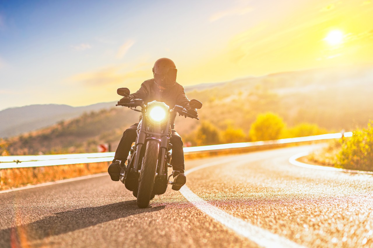 Motorcyclist riding a chopper on a road in morning sun