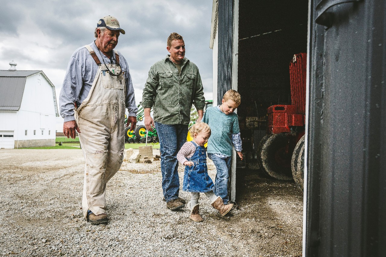 Three generations of farmers walking to a barn
