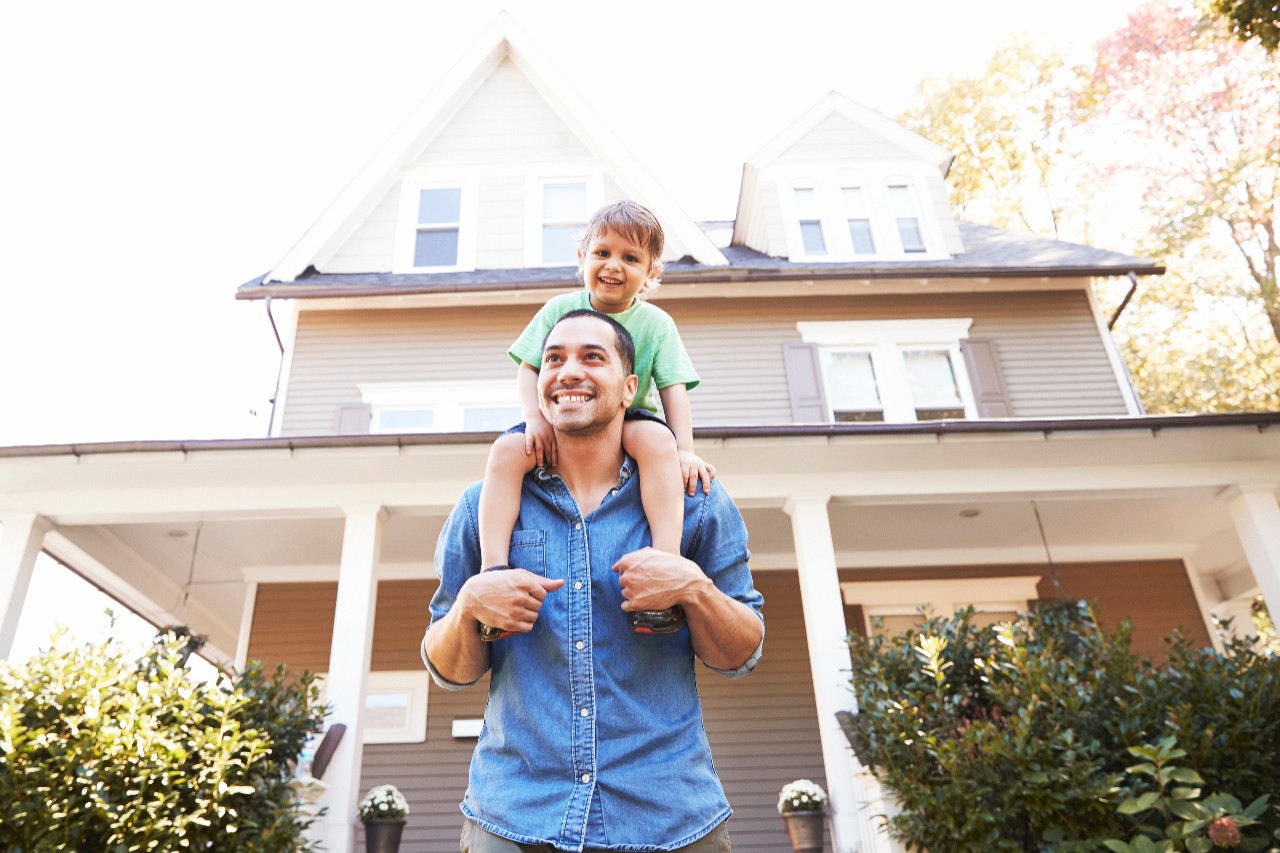 Father Giving Son Ride On Shoulders Outside House