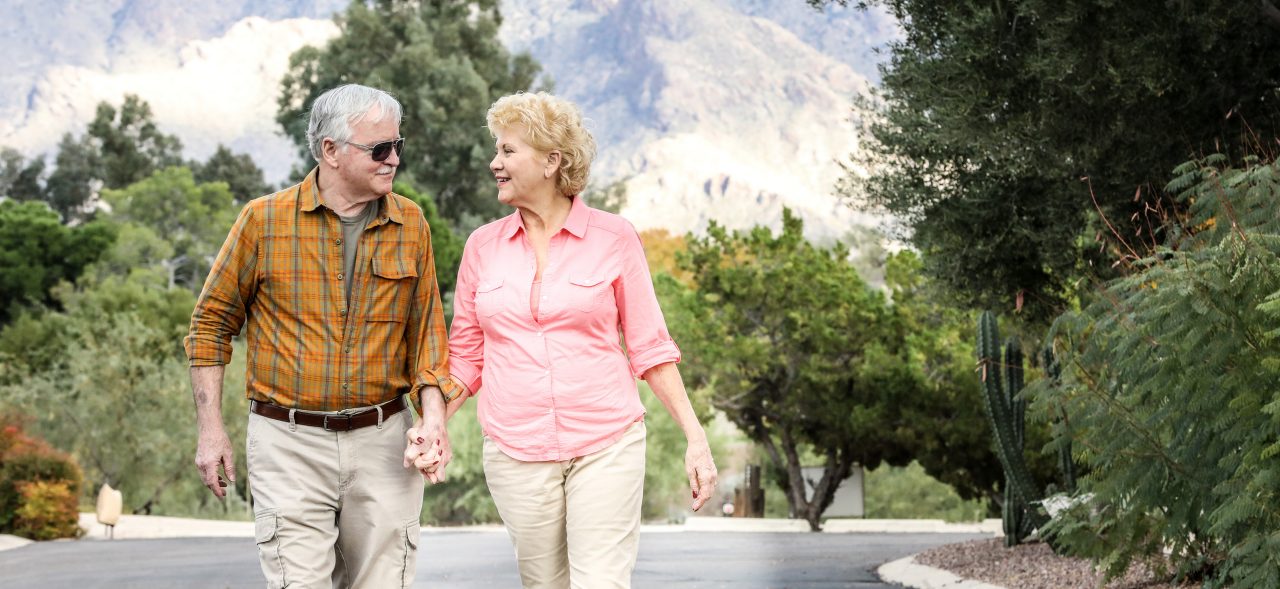 Senior couple holding hands walking on the road