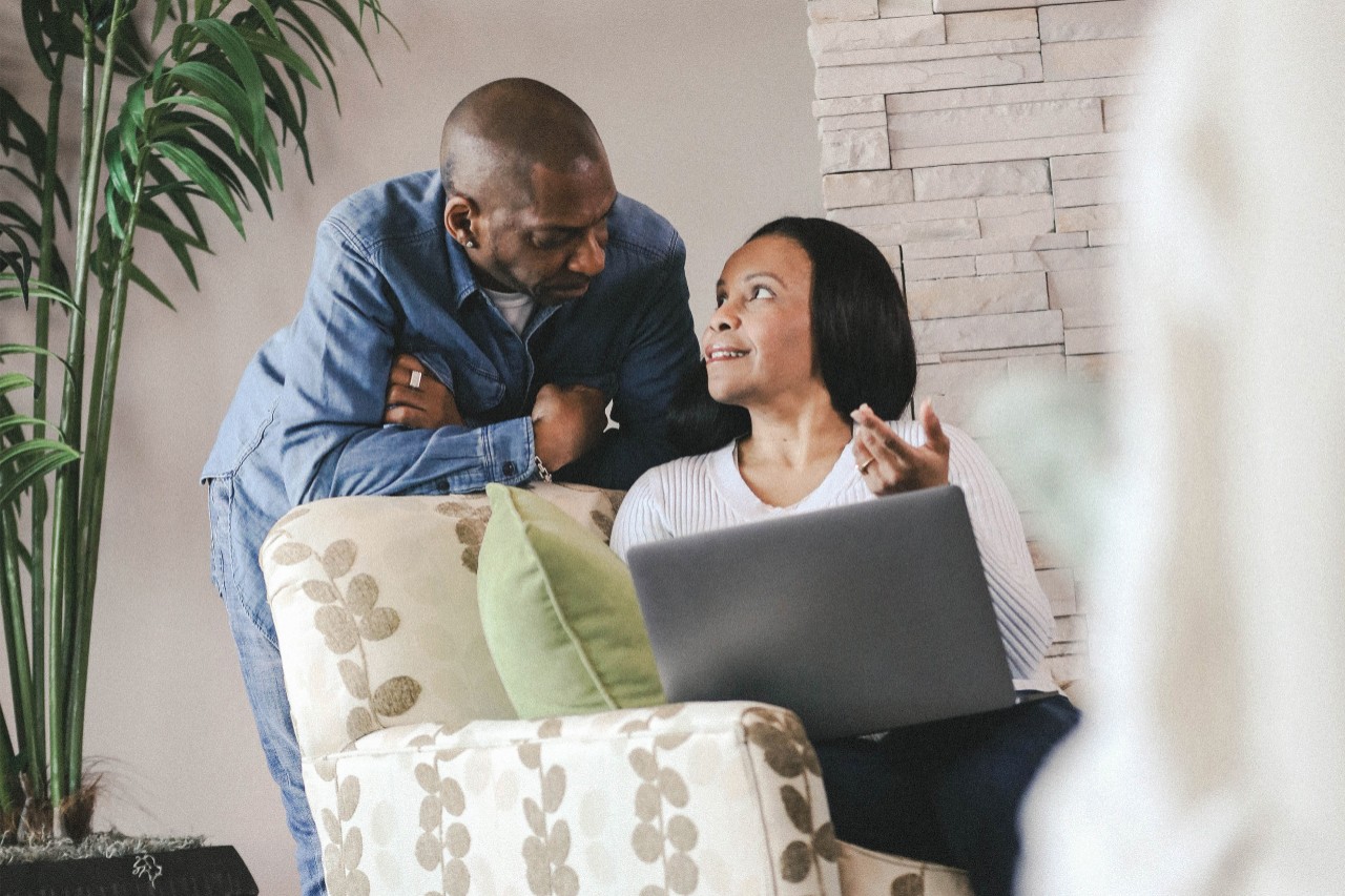 couple talking while holding open laptop