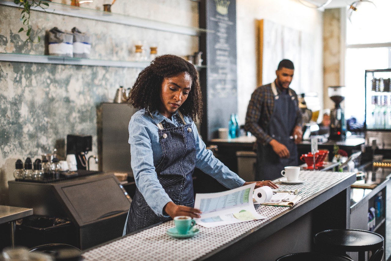 Business owner and barista at counter reviewing 401k plan