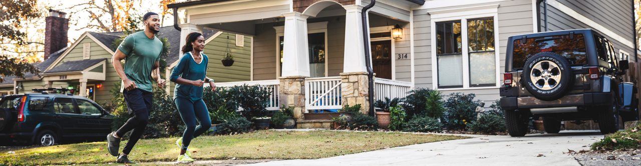 Couple on a run in front of house in neighborhood