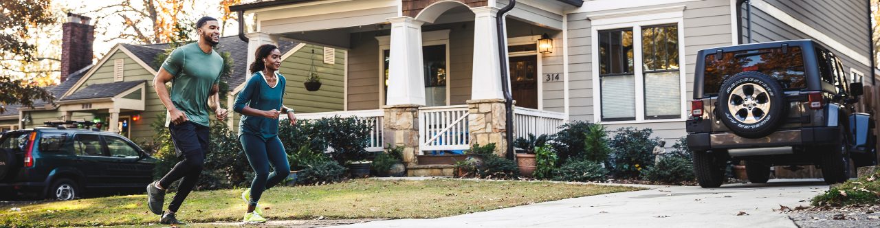 Couple on a run in front of house in neighborhood