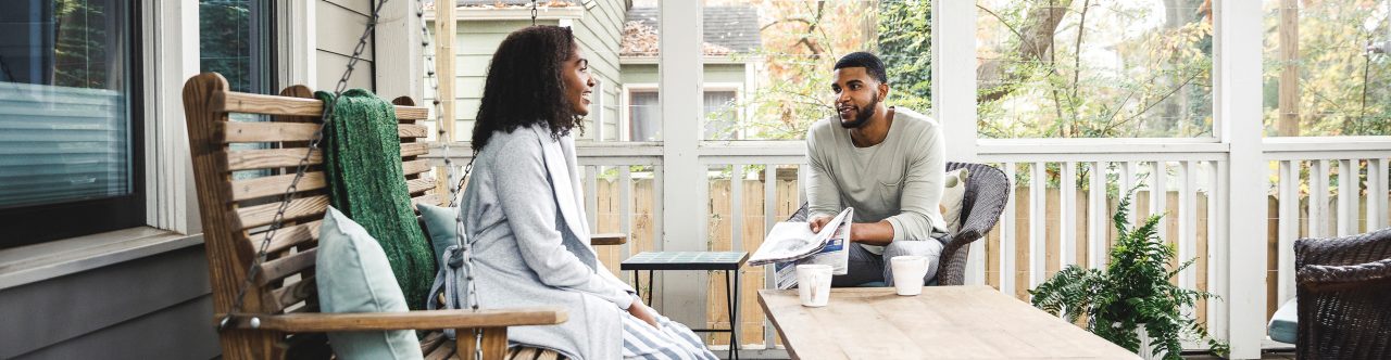Couple in pajamas sitting on porch furniture talking