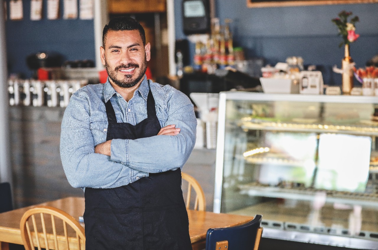 Smiling business owner with crossed arms standing in business