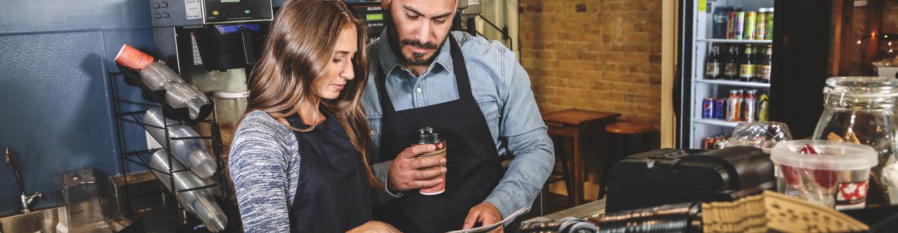 Business owner with worker reviewing paper behind counter