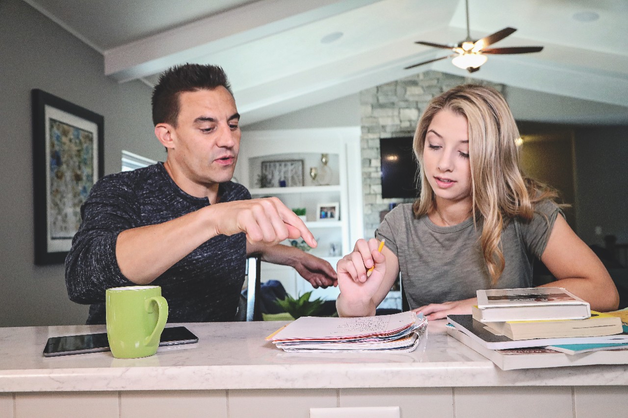 Father and daughter sitting at counter reviewing 529 plan