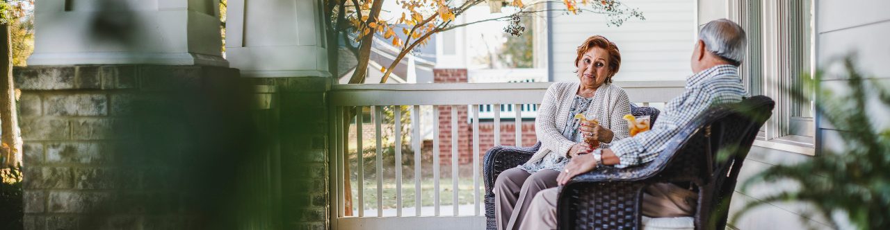 Senior couple sitting on front porch furniture 