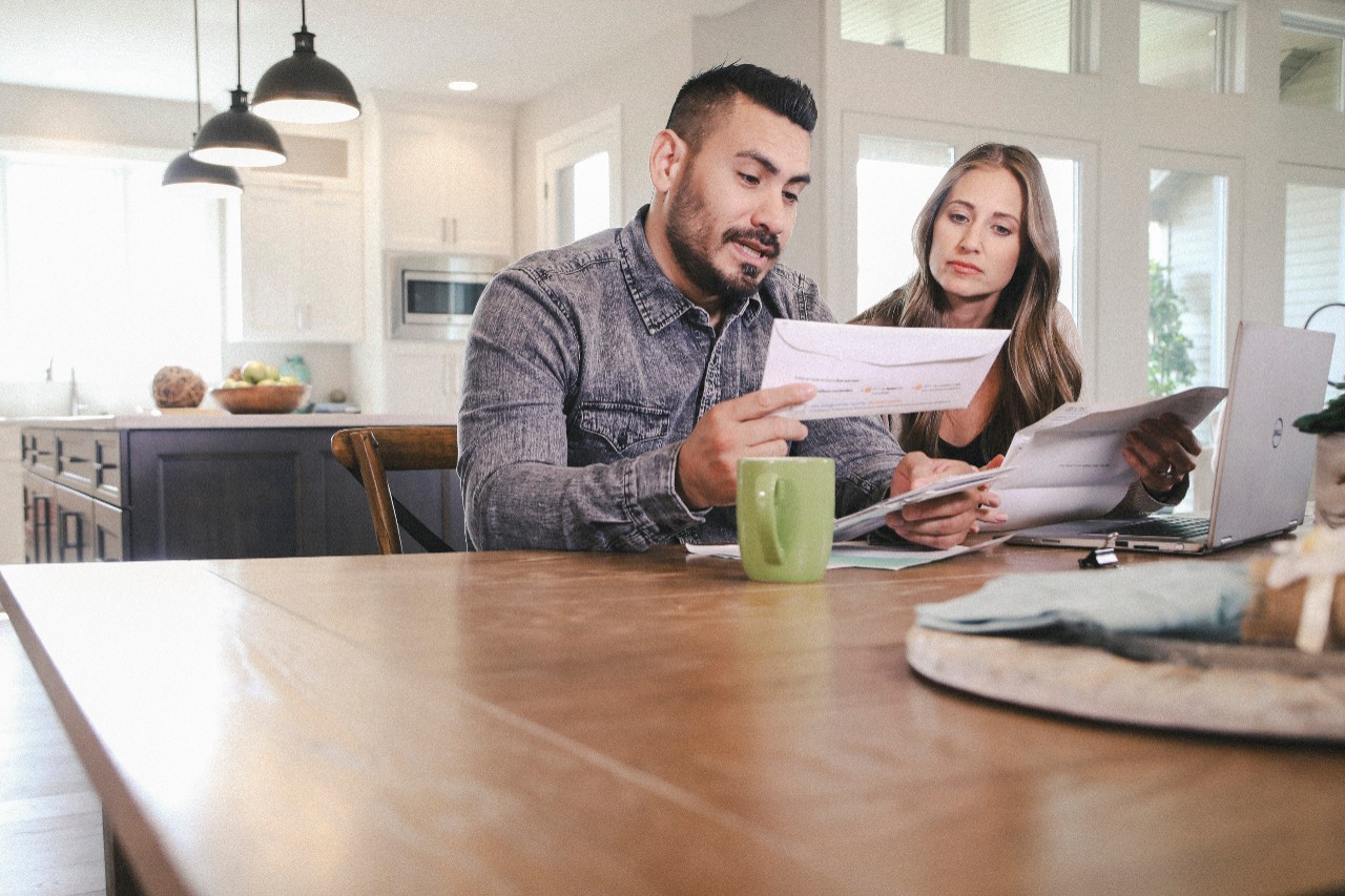 Couple reviewing bills at kitchen table in front of computer