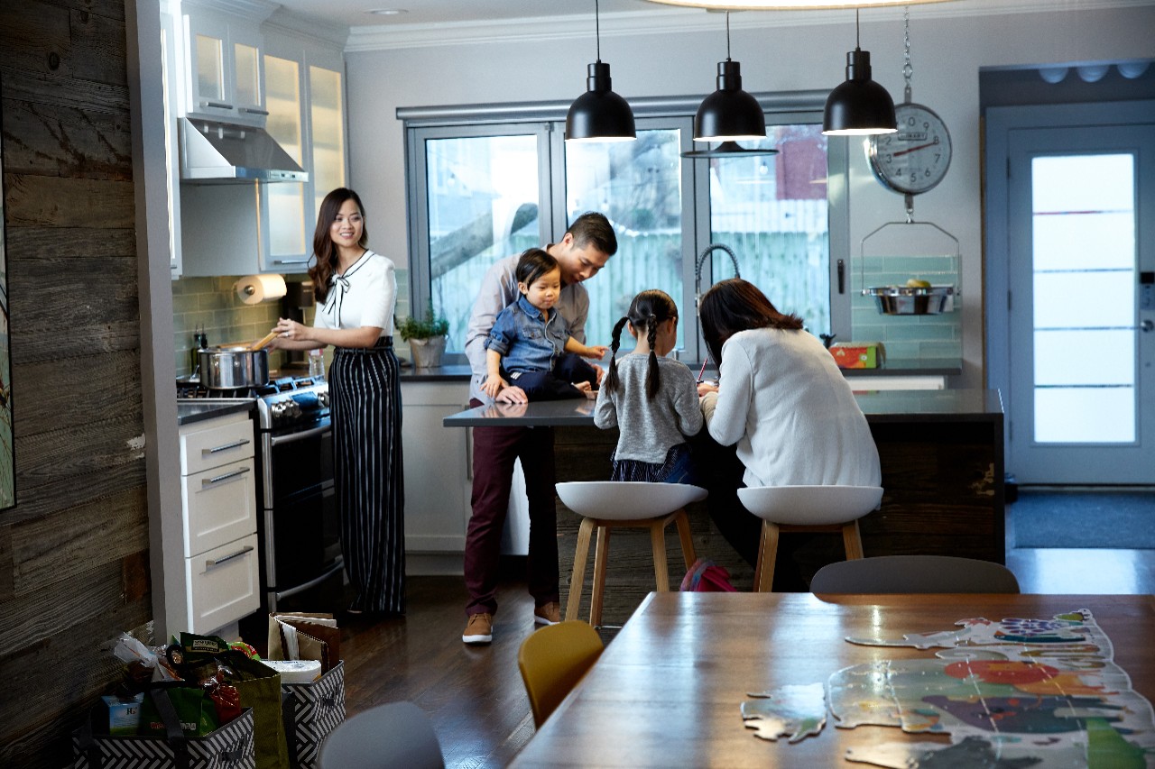 Young women preparing dinner while husband and grandma helps one of their daughters with homework