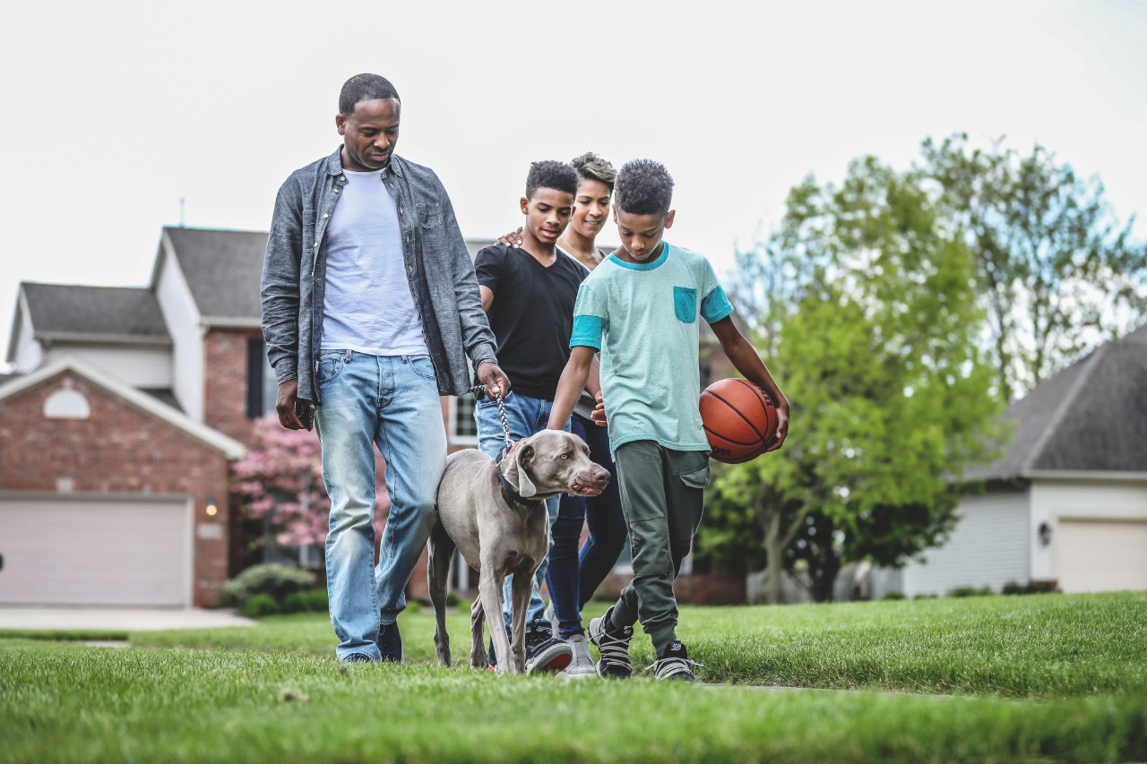 Family walking with dog in neighborhood.