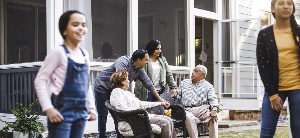 Family playing in yard and sitting in lawn furniture 