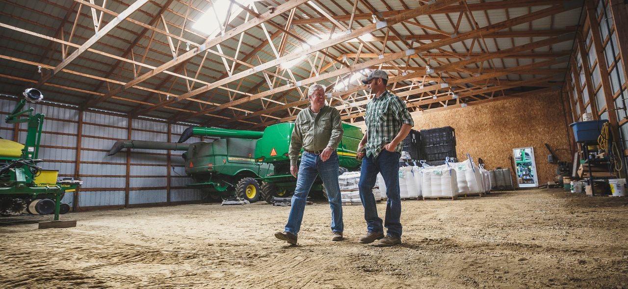 Two farmers walking inside barn