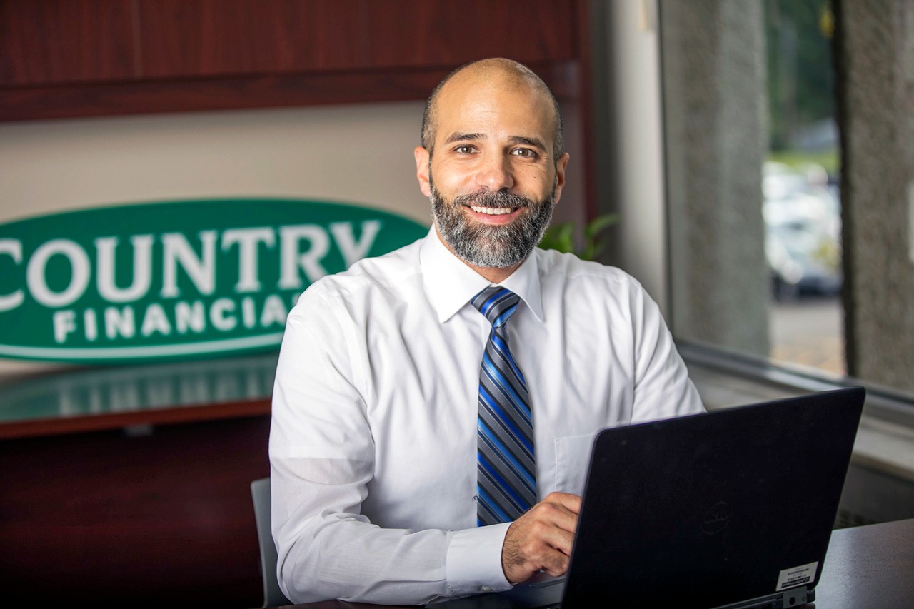 Smiling insurance agent at desk with laptop