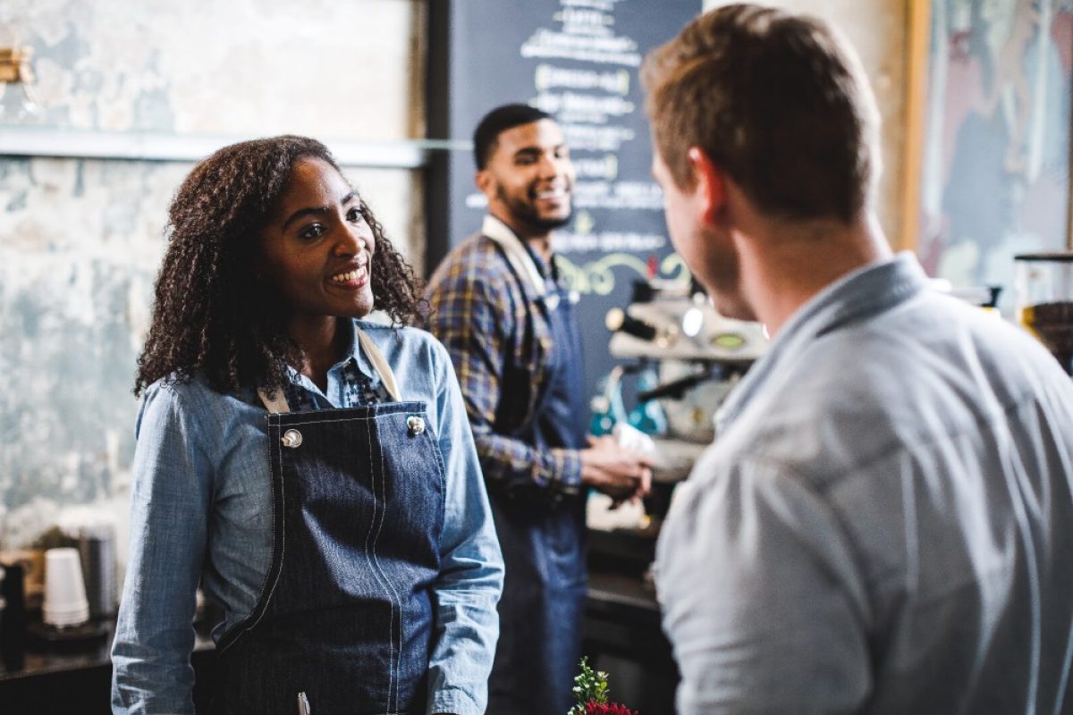 Coffeehouse workers talking to male customer