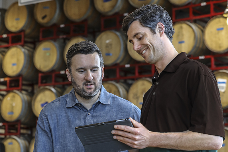 Insurance representative with brewery owner in barrel room